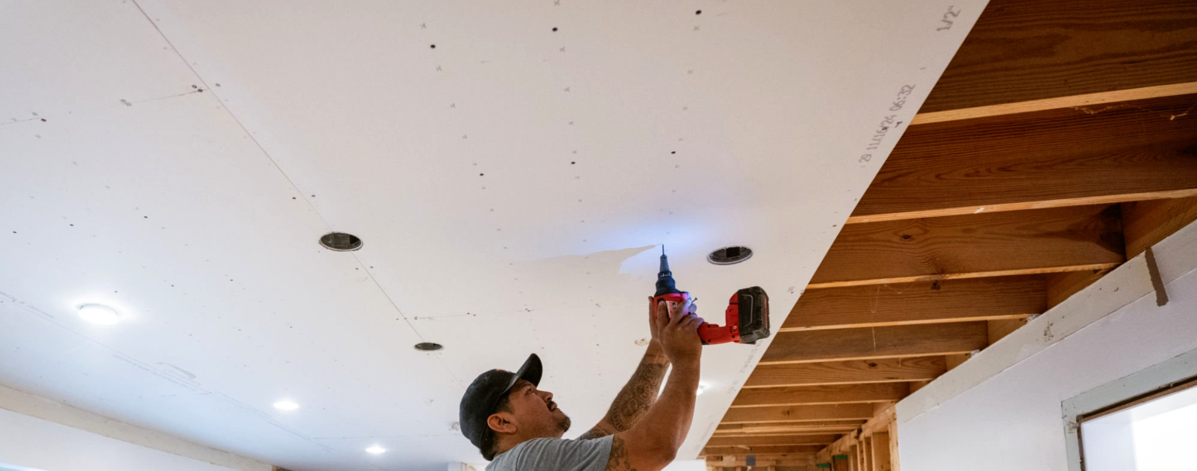 Installer drywalling a ceiling